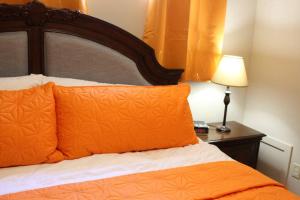 uma cama com almofadas laranja e uma mesa com um candeeiro em 2-Bedroom basement suite with a separate entrance. em Abbotsford