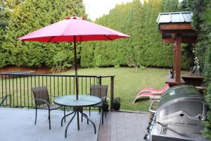 uma mesa com um guarda-chuva vermelho e uma grelha em 2-Bedroom basement suite with a separate entrance. em Abbotsford