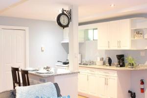 uma cozinha com armários brancos e um relógio na parede em 2-Bedroom basement suite with a separate entrance. em Abbotsford