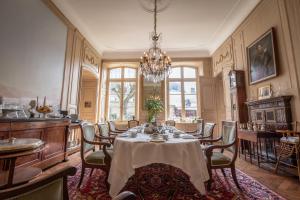 una sala da pranzo con tavolo, sedie e lampadario pendente di L'Hotel de Panette, Un exceptionnel château en ville a Bourges