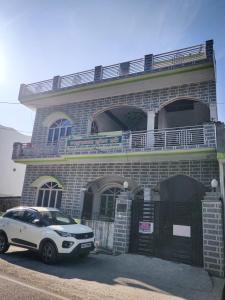デヘラードゥーンにあるGaharwar Home Stayのレンガ造りの建物の前に駐車した白車