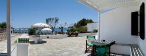 un patio con mesa, sillas y el océano en LEANDROS APARTMENTS en Platís Yialós Sifnos