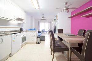 a kitchen with a dining table and a pink wall at Global Properties, Apartamento en la playa de Canet d'en Berenguer in Canet de Berenguer