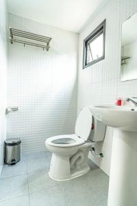 a white bathroom with a toilet and a sink at Laewan Guesthouse in Baan Tai