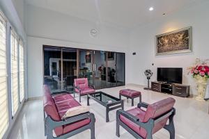 uma sala de estar com cadeiras cor-de-rosa e uma televisão em OYO 92057 Reny Kost Syariah em Jambi