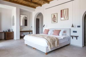 a white bedroom with a bed and a bathroom at Pelican Bay Hotel in Platis Gialos