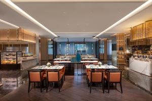 a restaurant with tables and chairs and a kitchen at HUALUXE Shanghai Changfeng Park by IHG in Shanghai