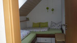 Habitación pequeña con cama con almohadas verdes en Ferienwohnung Holzheimer en Sandberg