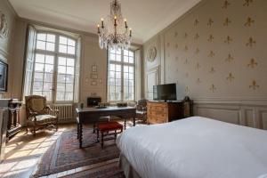 um quarto com uma cama, uma secretária e um lustre em L'Hotel de Panette, Un exceptionnel château en ville em Bourges