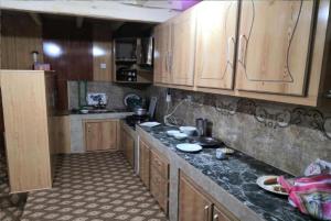 a kitchen with wooden cabinets and a black counter top at Sunrising Guest House Islamabad in Islamabad