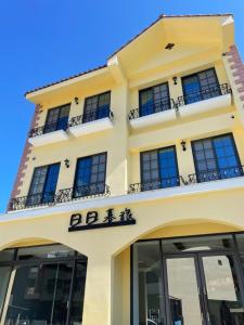 a yellow building with black windows and balconies at Daybyday Moon Homestay in Yuchi