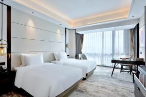 2 camas en una habitación de hotel con escritorio y 1 dormitorio en 银都酒店 Yandoo Hotel, en Yiwu