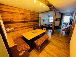 a dining room with a wooden wall and a table and benches at Natursport Heutal Appartements in Unken