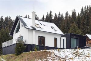een wit huis met een zwart dak op een heuvel bij CUBE Bucin in Bucin