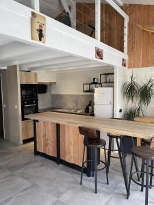 a kitchen with a wooden counter and stools at Une pause à la Hume in Gujan-Mestras