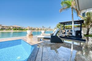 a swimming pool next to a villa with a swimming pool at Maison Privee - Glamourous Beachfront Villa on The Palm with Pool in Dubai