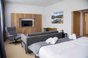 a bedroom with two beds and a tv and a chair at Family Resort Lučivná in Lučivná