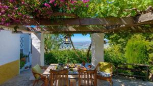 una mesa de comedor bajo una pérgola con flores en Casa Belmonte Alcaucín by Ruralidays, en Alcaucín