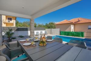 eine Terrasse mit einem Tisch und Stühlen sowie einem Pool in der Unterkunft Villa MONICA with private pool in Risika