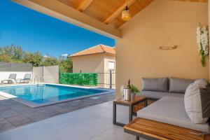 eine Terrasse mit einem Pool und einem Sofa in der Unterkunft Villa MONICA with private pool in Risika