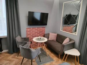 a living room with a couch and chairs and a tv at Apartament LUCY - ścisłe centrum Częstochowy in Częstochowa