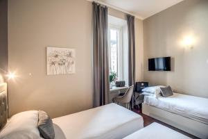 a hotel room with two beds and a desk at Hotel San Silvestro in Rome