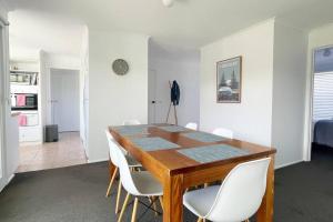 a dining room with a wooden table and white chairs at A Wave From It All in Torquay