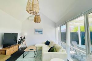 a living room with a white couch and a tv at A Wave From It All in Torquay
