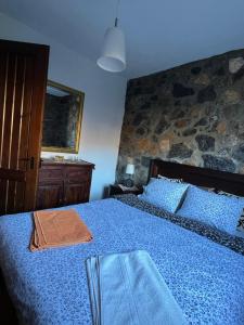 パライオス・アギオス・アタナシオスにあるMountain houseの石壁のベッドルーム1室(青いベッド1台付)