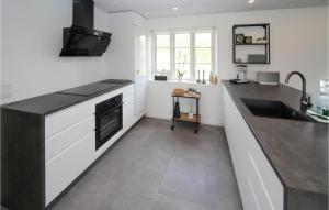 a kitchen with white cabinets and a black counter top at 4 Bedroom Gorgeous Home In Samsø in Ballen