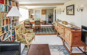 Awesome Home In Sams With Kitchen في Onsbjerg: غرفة معيشة مع مكتبة مع طاولة وكراسي