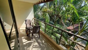 a balcony with two chairs and a view of palm trees at Palolem Inn in Palolem