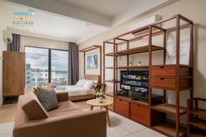 a living room with a couch and a tv at Timurbay Beachfront by Perfect Host in Kuantan