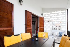a dining room with a wooden table and yellow chairs at Villa close to the beach in Nea Potidaea