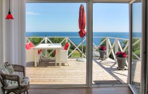 a balcony with a table and an umbrella and the ocean at Amazing Apartment In Gudhjem With 2 Bedrooms & Wifi in Gudhjem