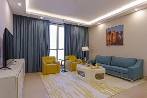a living room with a blue couch and yellow chairs at Sarwat Park Hotel Riyadh - Diplomatic Quarter in Riyadh