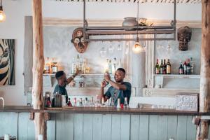 Dos hombres están haciendo bebidas en un bar en Sahari Zanzibar en Bwejuu