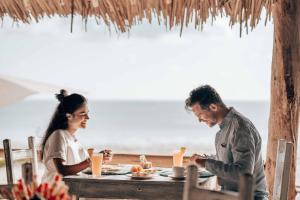 فندق صحاري زنجبار في بويجو: يجلس رجل وامرأة على طاولة على الشاطئ