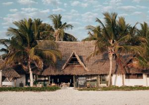 un restaurante en la playa con palmeras en Sahari Zanzibar en Bwejuu
