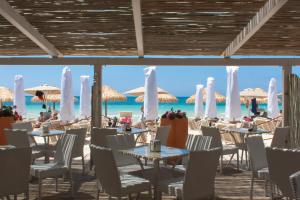 a restaurant on the beach with tables and chairs and umbrellas at Conchiglia Azzurra Resort & Beach in Porto Cesareo