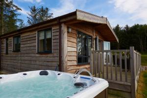 a large hot tub in front of a log cabin at Burgie Woodland Lodges in Forres