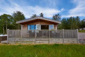 a small cabin with a fence in front of it at Burgie Woodland Lodges in Forres