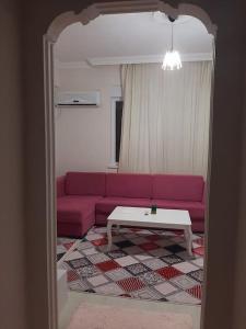 New renovated 1+1 flat in Kültür في أنطاليا: غرفة معيشة مع أريكة وردية وطاولة