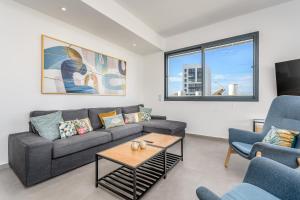 uma sala de estar com um sofá e duas cadeiras e uma mesa em Superb penthouse north tel aviv em Tel Aviv