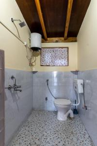 a bathroom with a toilet and a window in it at SaffronStays Altura, Mukteshwar - pahadi meals served at this orchard villa in Mukteswar +21 photos