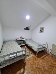 a bedroom with two beds and a wooden floor at Green door in Vrnjačka Banja