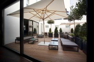a patio with benches and a large umbrella at Motel One Stuttgart-Mitte in Stuttgart