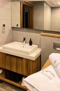 een badkamer met een witte wastafel en een spiegel bij Montes Szymoszkowa in Kościelisko