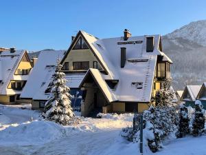 een huis bedekt met sneeuw en met sneeuw bedekte daken bij Montes Szymoszkowa in Kościelisko