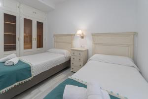 1 dormitorio blanco con 2 camas y vestidor en Apartamento El parador del boticario, en Cádiz